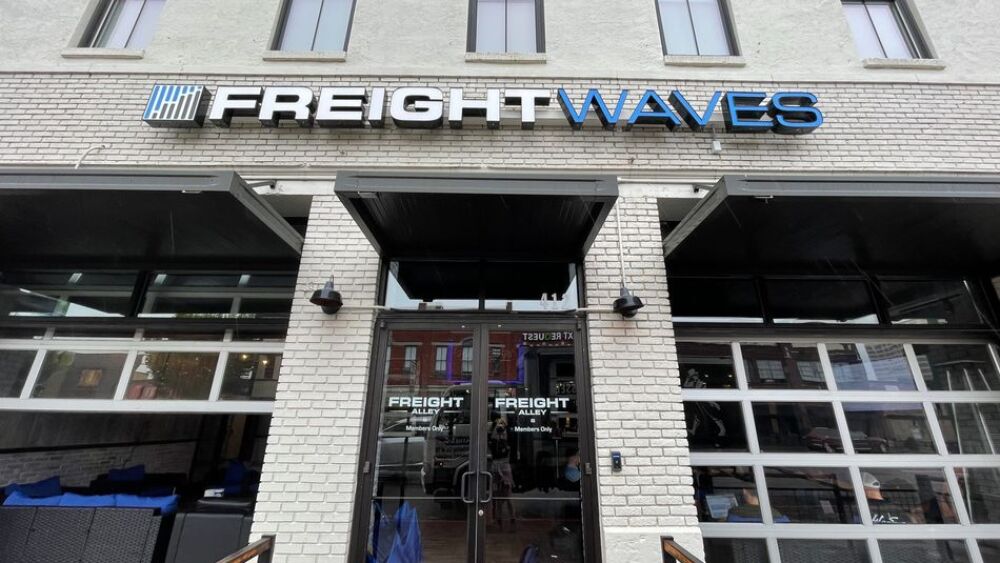 Photo of the front of the FreightWaves office in downtown Chattanooga. The photo features the front doors to the white brick building and the large "FreightWaves" sign above the doors.