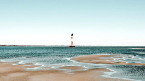 This photo shows the light house standing tall in the ocean.