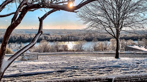 A bench in Libby Hill Park is covered in snow overlooking the river.