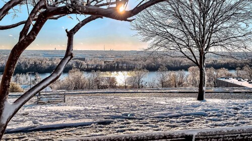 A bench in Libby Hill Park is covered in snow overlooking the river.