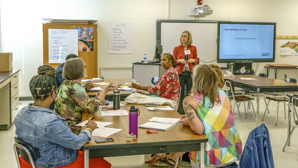 WStoday: teachers sitting around a table and listening to guest speaker making a presentation during Atkins high school leadership conference