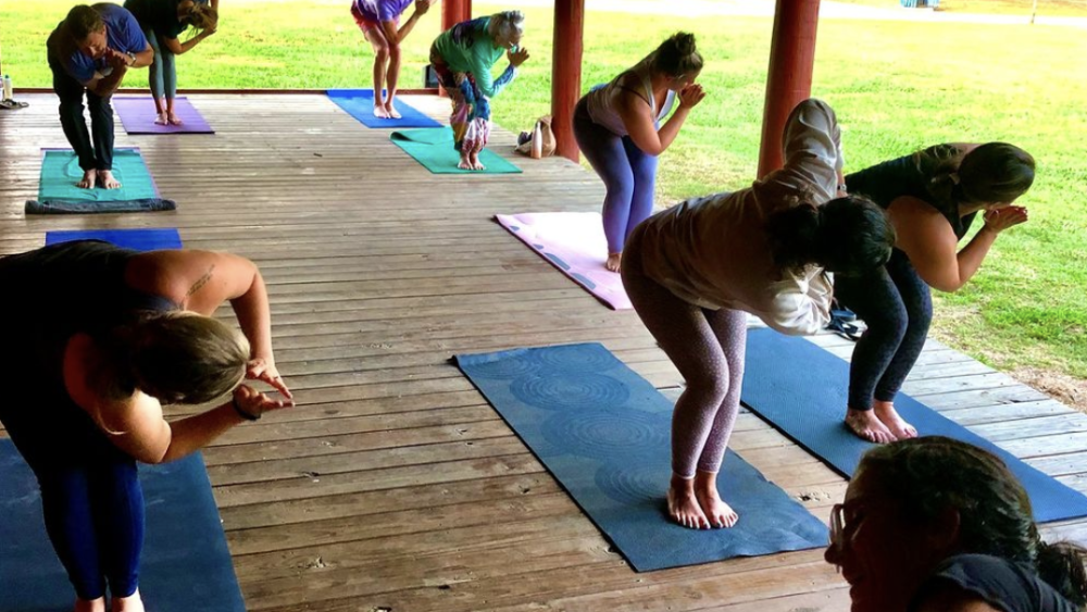 Several people posing in yoga class outdoors.