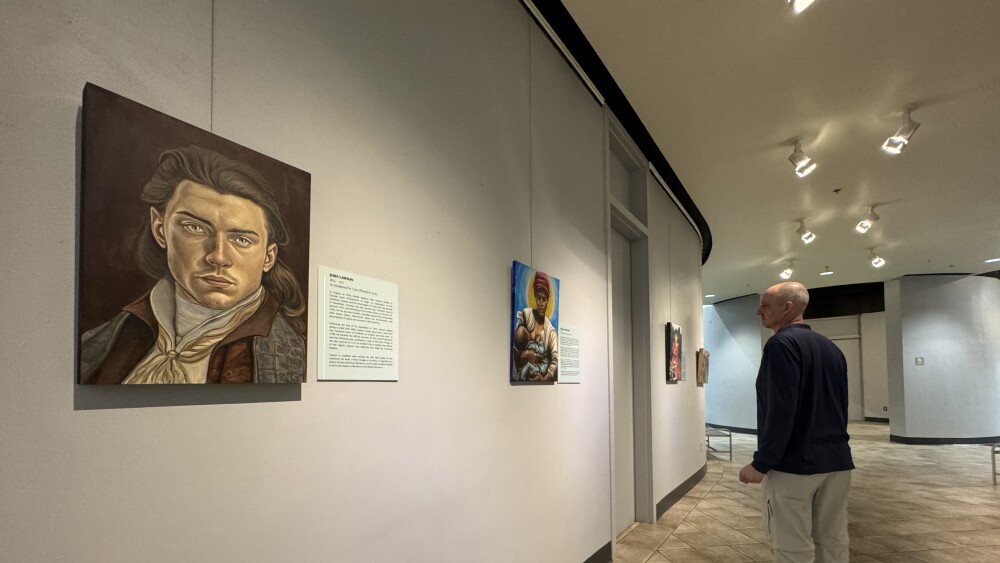 A hall with a portrait of John Lawson on the left and a man in the background looking at another portrait.