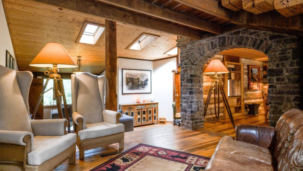 Cozy interior with stone archways, wood beams, and tall wingback chairs under warm lighting.