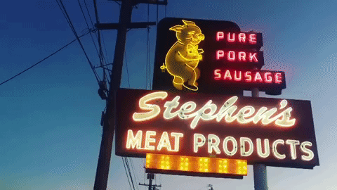 A GIF of a neon sign for "Stephen's Meat Products" with a dancing pig on it.
