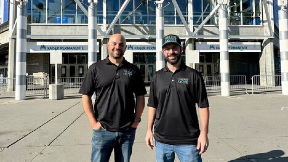 Aaron and Paul are wearing black shirts and jeans in front of the SAP Center in downtown San Jose.