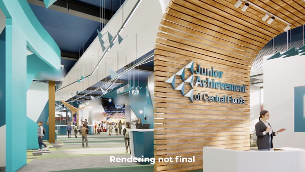 Rendering showing the inside of a building with blue and white walls and several geometric structures hanging from the ceiling. In the foreground, a curved wooden structure arches around a welcome desk and features text reading "Junior Achievement of Central Florida."