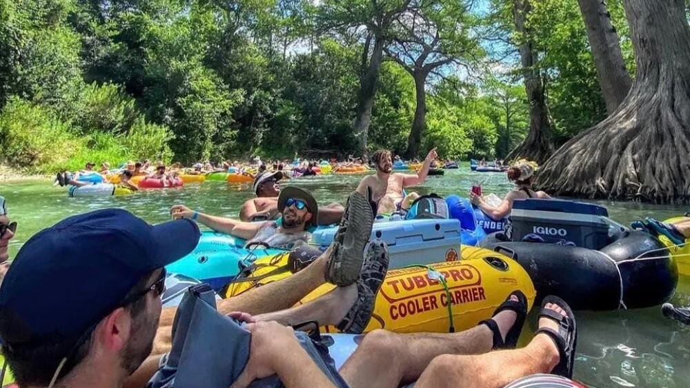 Group of friends enjoying a bright sunny day while floating down a river in tubes.