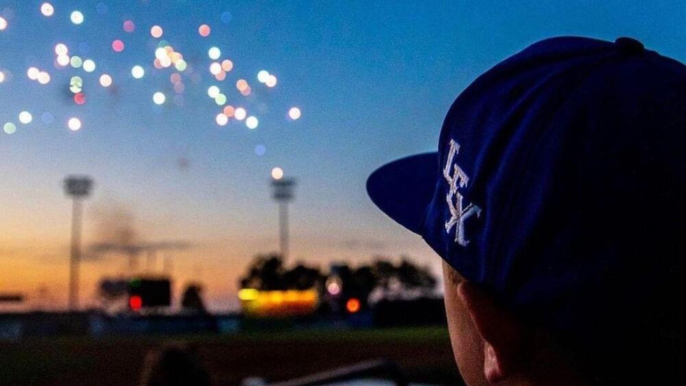 A man wearing a baseball hat watches fireworks
