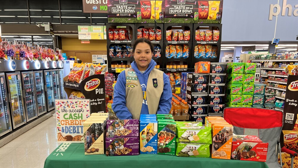 girl scout stand with table full of cookies