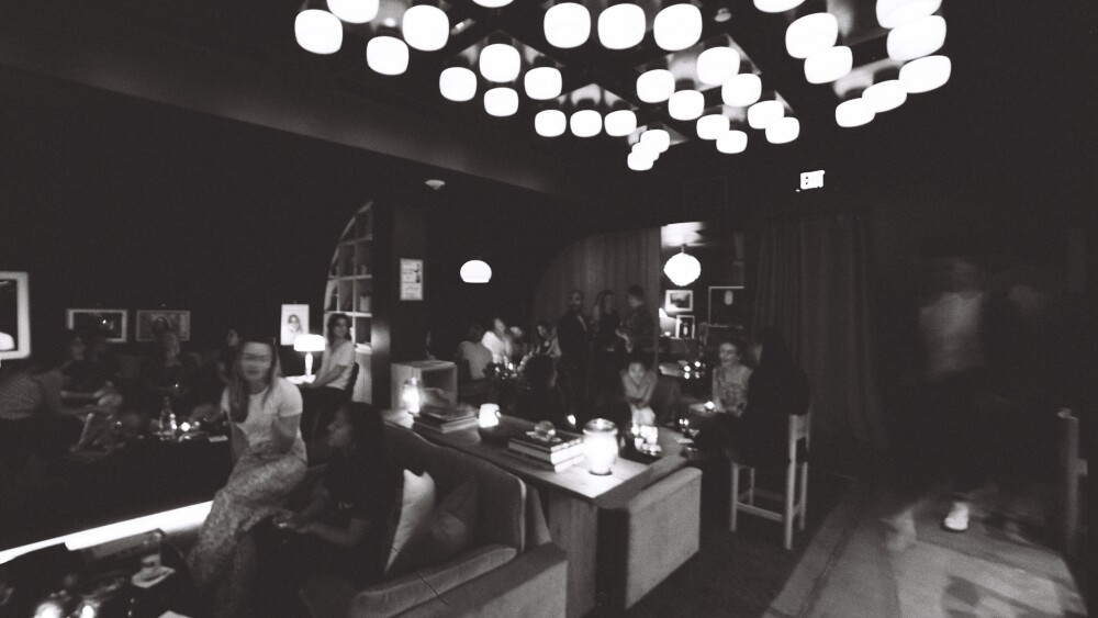 A blurry, black and white photo of people enjoying a party in a ritzy lounge.